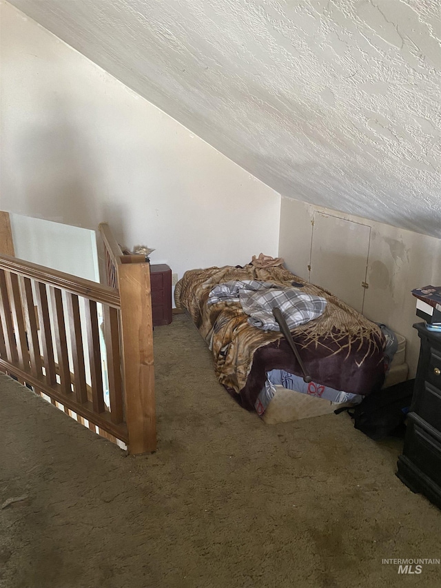 unfurnished bedroom with a textured ceiling, lofted ceiling, and carpet