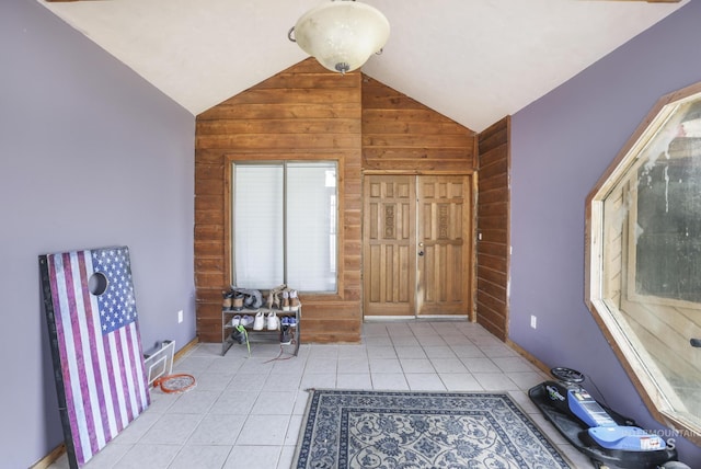 interior space with vaulted ceiling, wooden walls, and light tile patterned floors