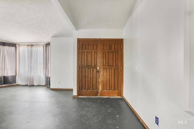 entrance foyer featuring concrete floors and baseboards