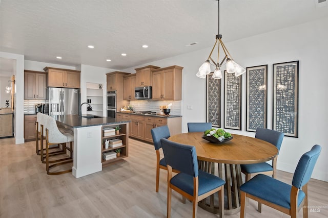 dining room featuring sink, light hardwood / wood-style floors, and a chandelier