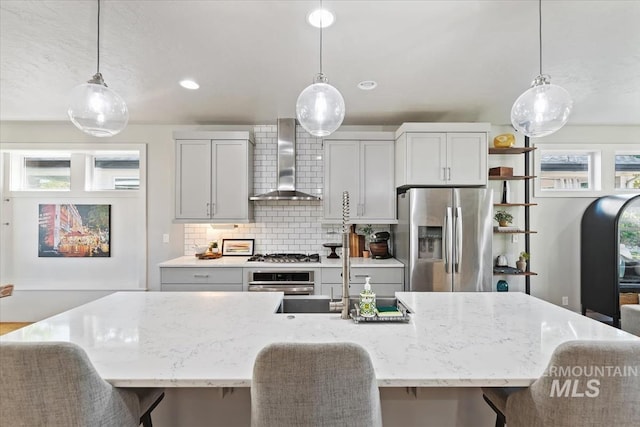 1765 E Bergeson St, Boise, ID 83706 - kitchen with stainless steel appliances, wall chimney range hood, backsplash, a kitchen breakfast bar, and a center island with sink