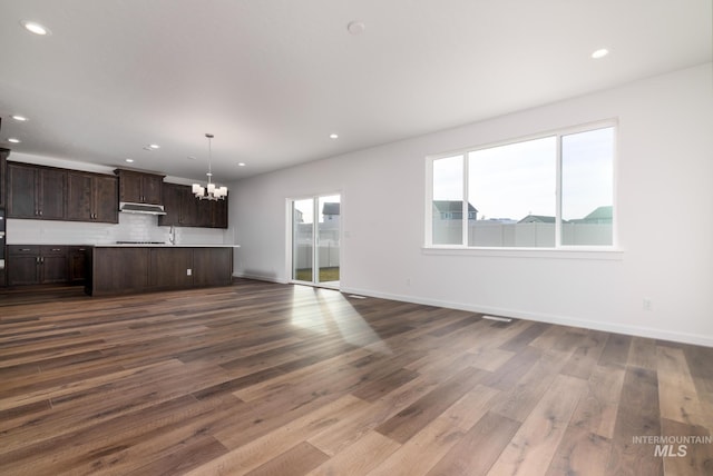 unfurnished living room featuring an inviting chandelier and wood-type flooring