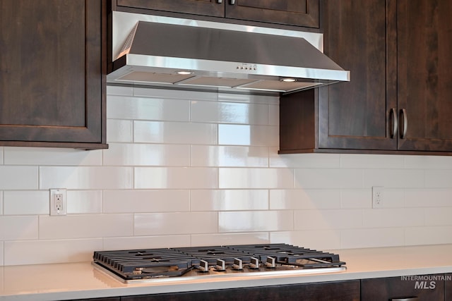 kitchen with backsplash, dark brown cabinetry, wall chimney exhaust hood, and stainless steel gas cooktop