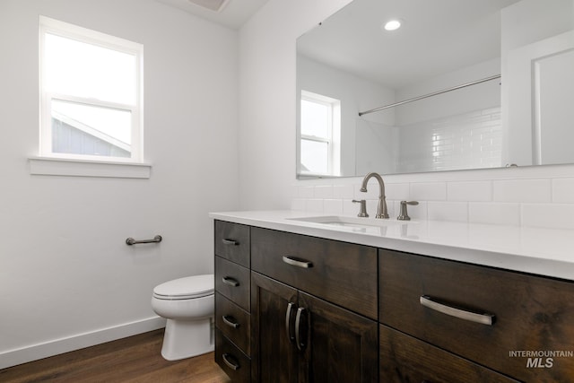 bathroom with hardwood / wood-style floors, decorative backsplash, toilet, and vanity