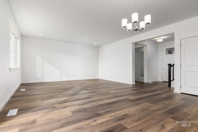 empty room featuring a notable chandelier and dark hardwood / wood-style flooring