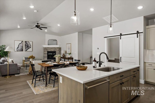 kitchen with open floor plan, dishwasher, a barn door, and a sink