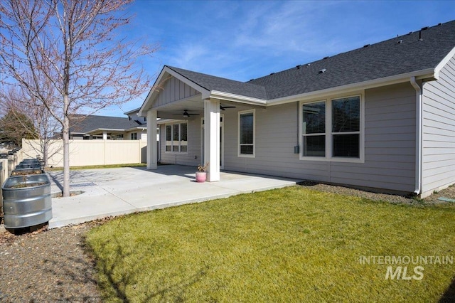 rear view of property featuring a shingled roof, fence, a lawn, a patio area, and a ceiling fan