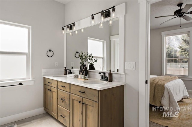 full bath with double vanity, a ceiling fan, ensuite bathroom, and a sink