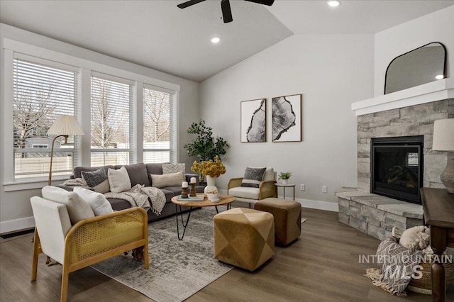 living room with wood finished floors, a stone fireplace, baseboards, ceiling fan, and vaulted ceiling