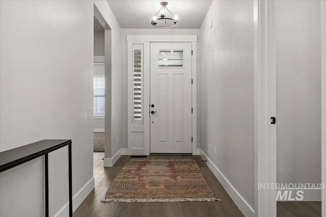 foyer entrance with dark wood-style floors and baseboards