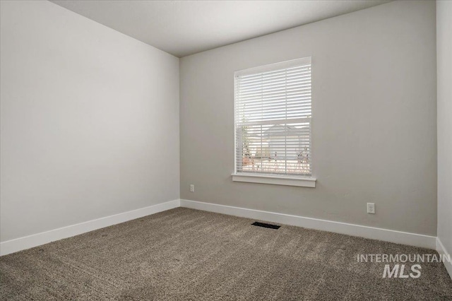 empty room featuring visible vents, baseboards, and carpet