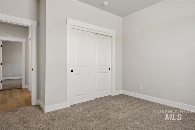 unfurnished bedroom with a closet, baseboards, and carpet floors