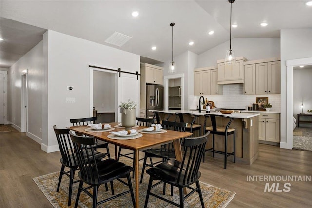 dining room with baseboards, high vaulted ceiling, recessed lighting, dark wood-type flooring, and a barn door