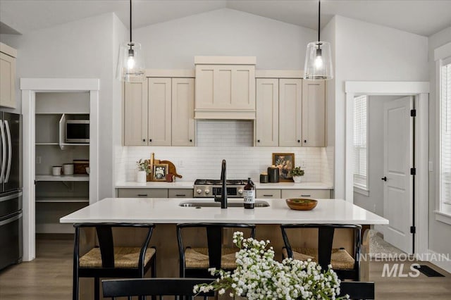 kitchen featuring stainless steel microwave, freestanding refrigerator, vaulted ceiling, and light countertops