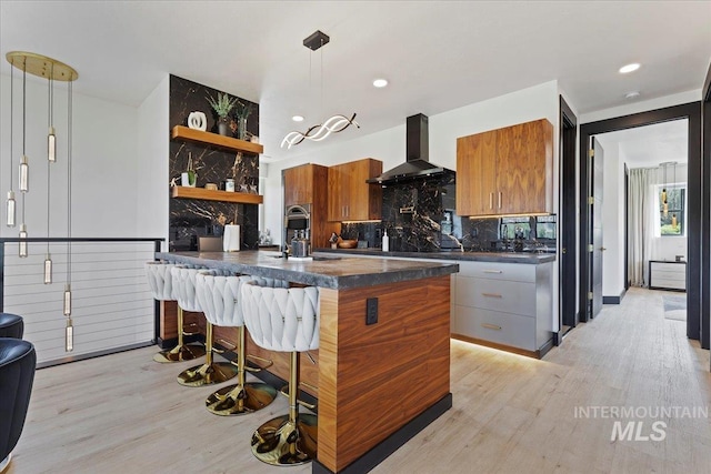 15 Alder Creek Ln, Garden Valley, ID 83622 - kitchen featuring dark countertops, wall chimney exhaust hood, light wood-style flooring, open shelves, and brown cabinetry