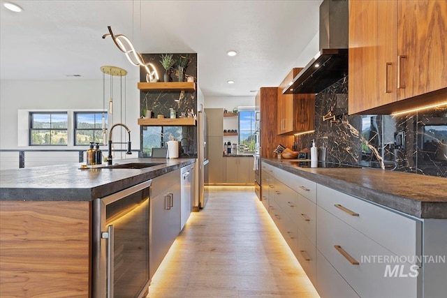 15 Alder Creek Ln, Garden Valley, ID 83622 - kitchen featuring wall chimney range hood, beverage cooler, modern cabinets, light wood finished floors, and decorative backsplash