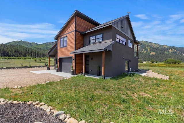 15 Alder Creek Ln, Garden Valley, ID 83622 - view of front of home featuring concrete driveway, a garage, a mountain view, and a front lawn