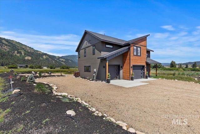 15 Alder Creek Ln, Garden Valley, ID 83622 - view of side of property featuring a garage, driveway, a mountain view, and stucco siding