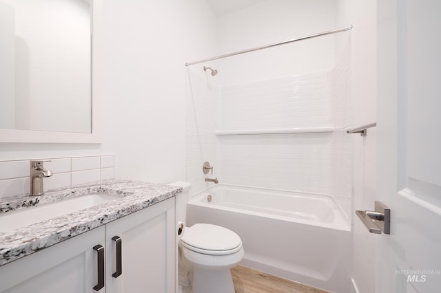 full bathroom with tasteful backsplash, vanity, toilet, wood finished floors, and washtub / shower combination