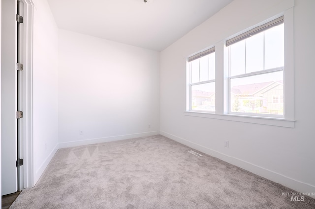 carpeted spare room featuring baseboards and visible vents
