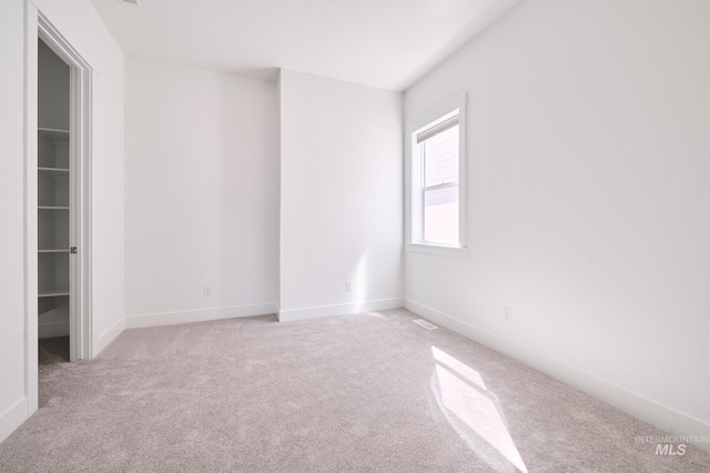 carpeted spare room featuring baseboards