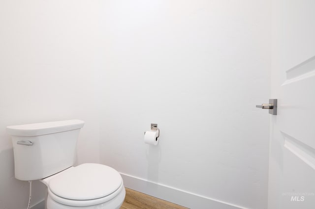 bathroom featuring toilet, wood finished floors, and baseboards