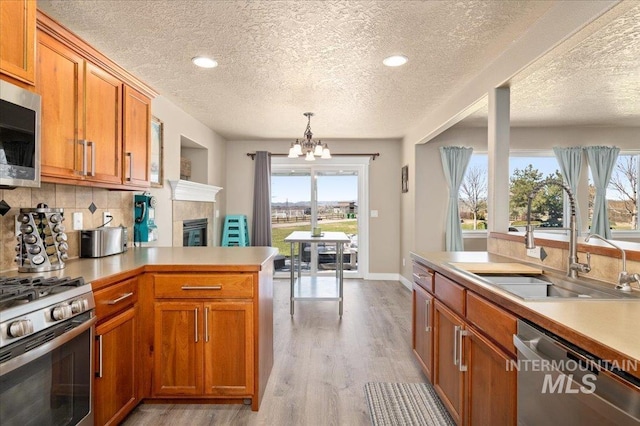 1375 Ross Rd, Weiser, ID 83672 - kitchen featuring stainless steel appliances, a textured ceiling, a chandelier, brown cabinets, and a peninsula
