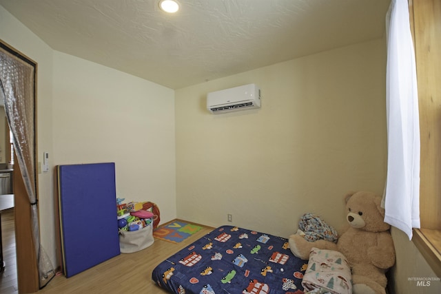 bedroom featuring a wall mounted AC and wood finished floors