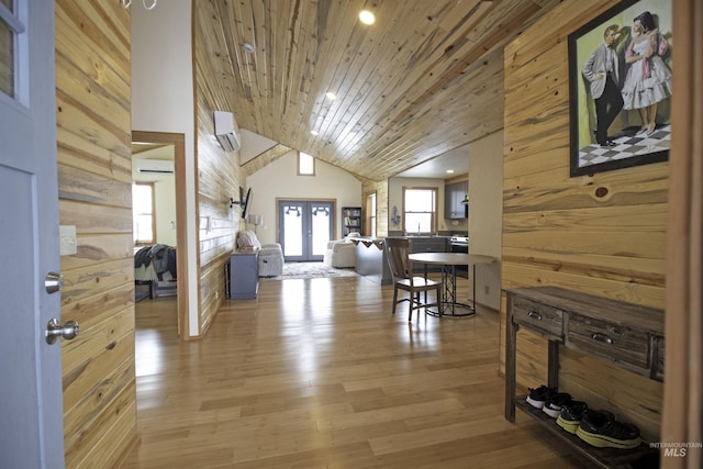 dining area featuring wooden walls, a wall unit AC, wood ceiling, light wood-style flooring, and french doors