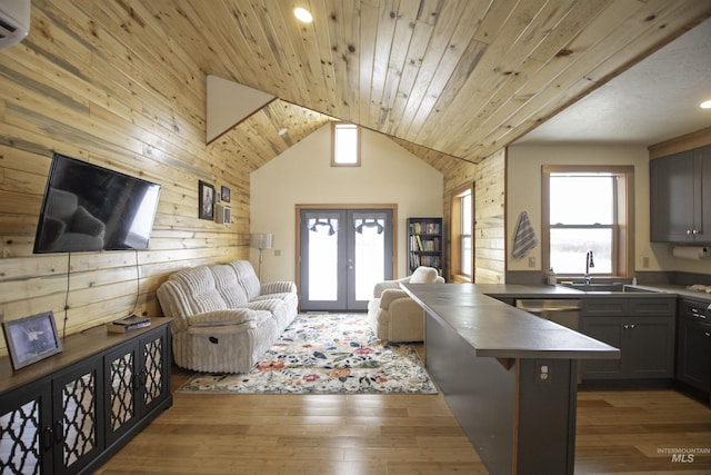 kitchen with french doors, stainless steel countertops, wood ceiling, open floor plan, and a sink