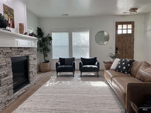 4446 S Carina Way, Meridian, ID 83642 - living area featuring a stone fireplace, light wood-style floors, and a textured ceiling