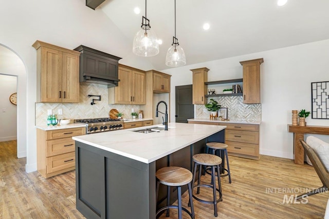 968 Gregory Way, Twin Falls, ID 83301 - kitchen featuring tasteful backsplash, light wood-style floors, a kitchen island with sink, a kitchen breakfast bar, and arched walkways