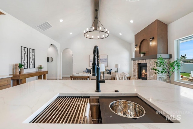 968 Gregory Way, Twin Falls, ID 83301 - kitchen featuring arched walkways, a chandelier, light stone countertops, open floor plan, and a tile fireplace