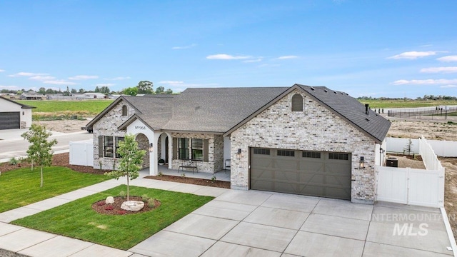 968 Gregory Way, Twin Falls, ID 83301 - french country style house featuring driveway, an attached garage, a gate, roof with shingles, and brick siding