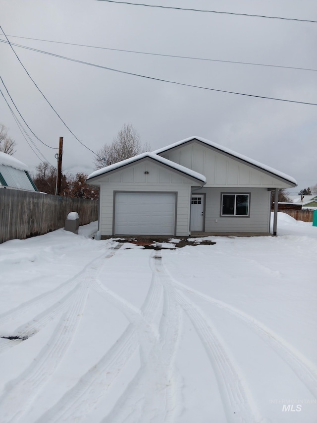 view of front of home with board and batten siding, an attached garage, and fence