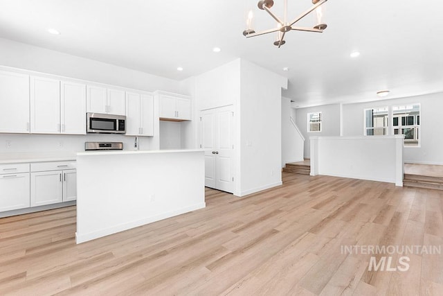 1609 N Impreza Ln Lot 24/1, Boise, ID 83713 - kitchen with stainless steel microwave, open floor plan, white cabinetry, light wood-type flooring, and light countertops