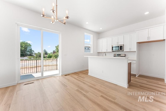 1609 N Impreza Ln Lot 24/1, Boise, ID 83713 - kitchen featuring stainless steel microwave, a chandelier, light wood finished floors, white cabinets, and light countertops