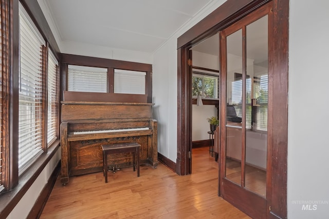 living area with ornamental molding, wood finished floors, and baseboards