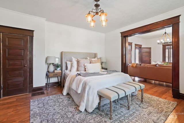 bedroom featuring a chandelier, ornamental molding, wood finished floors, and baseboards