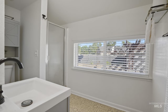 bathroom with a sink, a shower stall, and baseboards