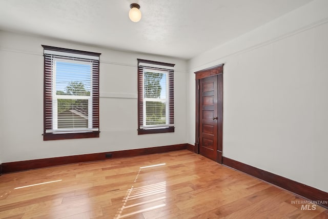 empty room featuring baseboards, plenty of natural light, and light wood-style floors