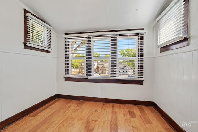 empty room featuring light wood-style floors, baseboards, and a wealth of natural light