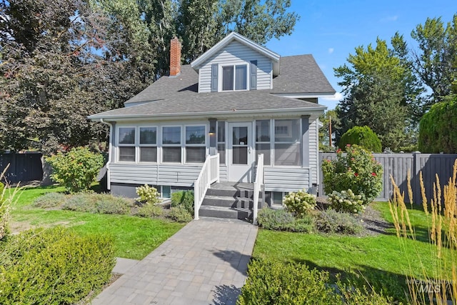 bungalow with a front lawn, a chimney, fence, and a sunroom