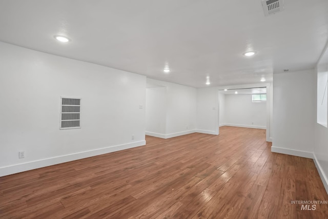 below grade area with hardwood / wood-style flooring, baseboards, and visible vents