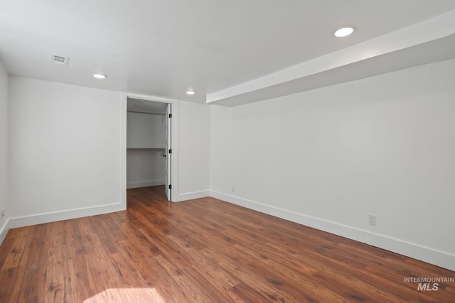 unfurnished bedroom with wood finished floors, visible vents, baseboards, a spacious closet, and a closet