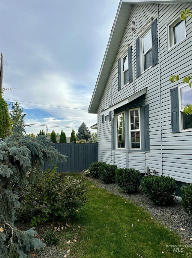 view of side of home with fence and a lawn