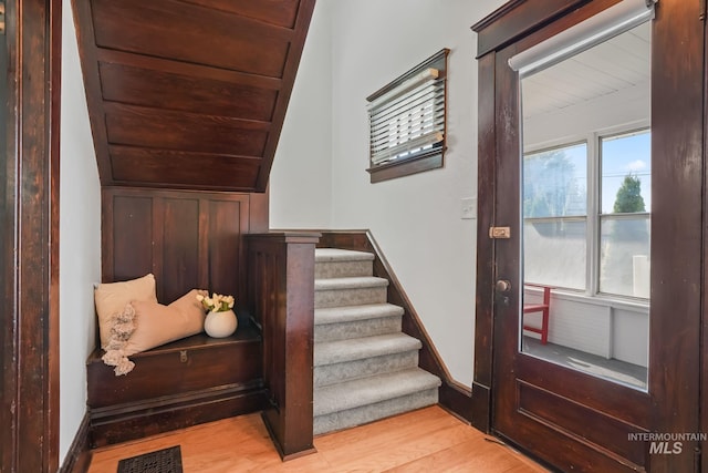 stairs with visible vents, baseboards, wooden ceiling, wood finished floors, and vaulted ceiling