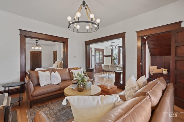 living room with an inviting chandelier, crown molding, and wood finished floors