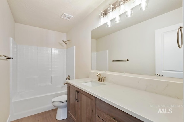 bathroom with visible vents, toilet, wood finished floors, vanity, and shower / bath combination