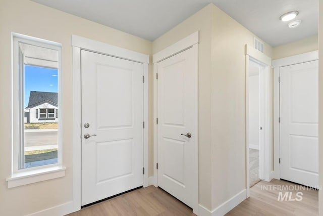 foyer entrance with baseboards, visible vents, and light wood finished floors